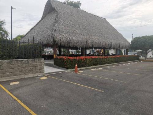 a building with a straw roof with a parking lot at Agradable casa con piscina en tierra caliente in Flandes