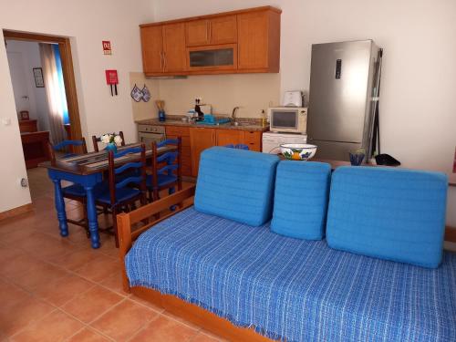 eine Küche mit einem blauen Sofa und einem Tisch mit einem Kühlschrank in der Unterkunft Casinha de férias no campo - Quintinha dos Cavalos - Arruda dos Vinhos in Sabugos