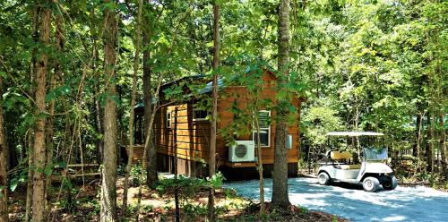 uma pequena casa com um carrinho de golfe na floresta em Broad River Campground Cabins & Domes em Boiling Springs