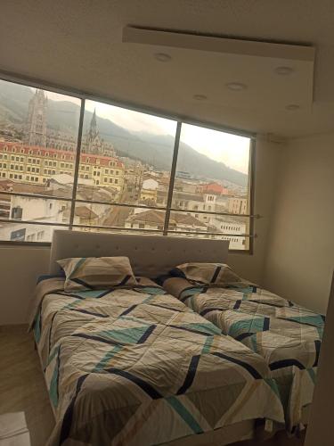 zwei Betten in einem Zimmer mit großem Fenster in der Unterkunft Vive el esplendor del Centro Histórico in Quito