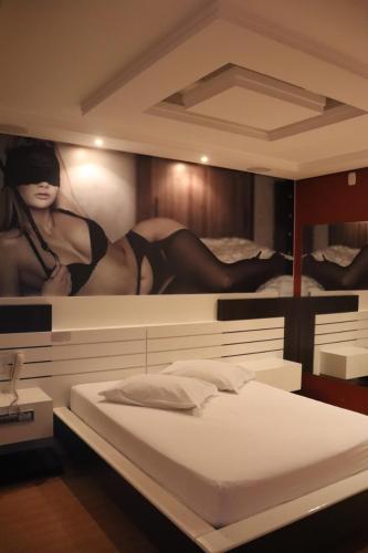 a bedroom with a bed with a painting of a woman at Motel Chevalier in Lages