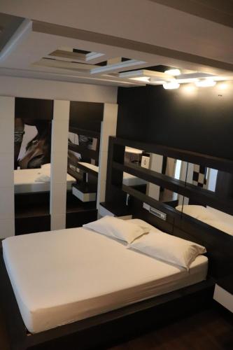 um quarto com uma cama grande e lençóis brancos em Motel Chevalier em Lages