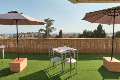 a table and two chairs and an umbrella on a lawn at Hotel Astoria in Bordighera