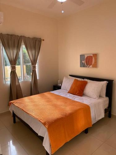 ein Schlafzimmer mit einem Bett mit einer orangefarbenen Decke in der Unterkunft Lovely 2 Bedroom Apartment in Quiet Neighborhood! in Philipsburg