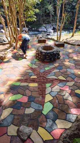 a person is working on a colorful stone patio with a fire pit at Estalagem do Rancho in Itatiaia