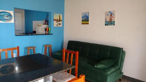 ein Wohnzimmer mit einem grünen Sofa und einem Tisch in der Unterkunft Recanto das Pedras - CASA Pedra Portuguesa - Com vista para o mar in Jaguaruna