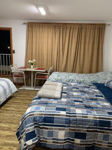 a bedroom with a bed and a table with a tableablish at Apart Hotel Vicencio Iquique in Iquique