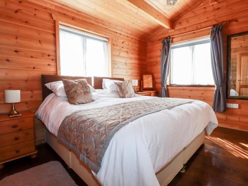 um quarto com uma cama num chalé de madeira em Willow Lodge em Bodmin