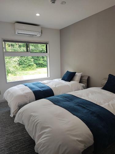 three beds in a room with a window at Hakuba Sunrise Apartments in Hakuba