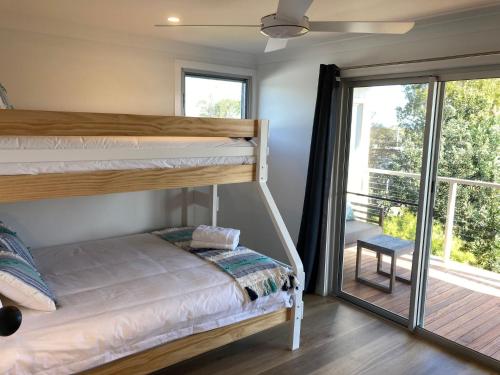 a bedroom with bunk beds and a balcony at Beachcomber at Currarong - Pet Friendly - 5 Mins Walk to Currarong Rockpools in Currarong