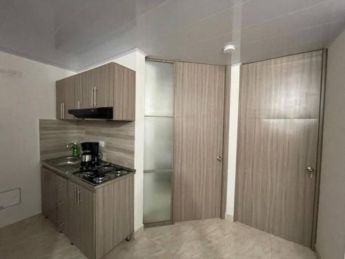 a kitchen with wooden cabinets and a stove in it at Hermoso apartamento completo 2 habitaciones - ubicación excelente para transporte al parque del café y PANACA in Armenia