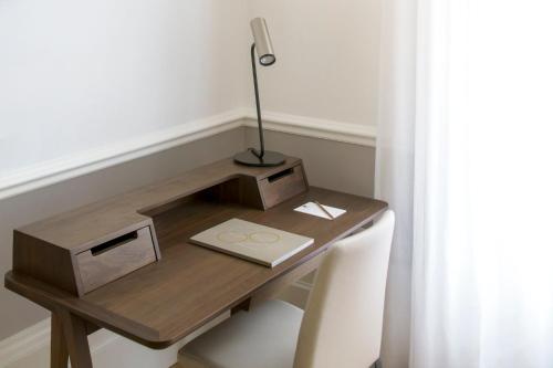 a wooden desk with a lamp on it next to a window at COMO Metropolitan London in London