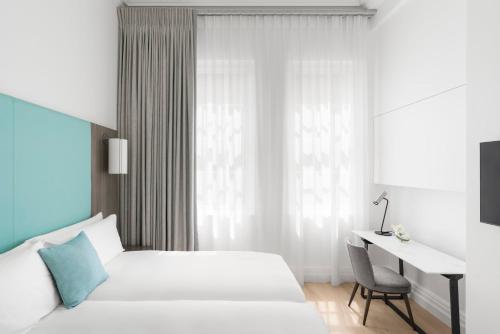 a white bedroom with a desk and a bed and a bedskirts at COMO Metropolitan London in London
