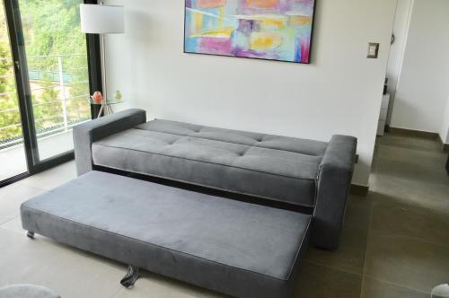 a gray couch in a living room with a painting at Cozy Stays Cayala Apartments (407) in Guatemala