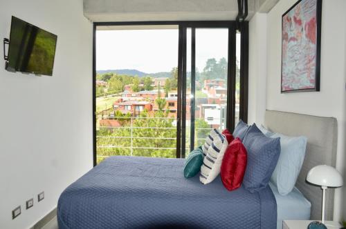 a bedroom with a blue bed with a large window at Cozy Stays Cayala Apartments (407) in Guatemala
