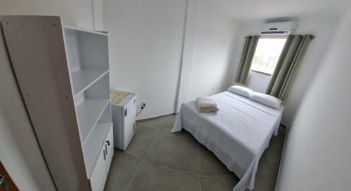 een kleine kamer met een bed en een raam bij Kitnet Super in Cumuruxatiba