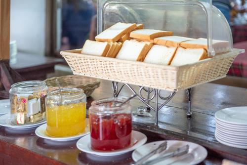 a basket of cheese and jam on a table with plates at The Legacy River Kwai Resort in Kanchanaburi