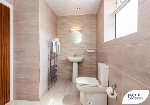 a bathroom with a toilet and a sink and a mirror at Dene Hotel in Newcastle upon Tyne