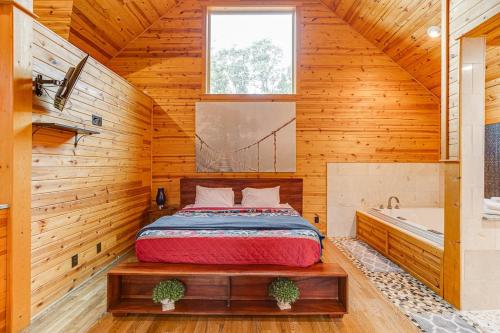 1 dormitorio con 1 cama y bañera en una habitación en Perfect Couples Cabin w 2 Person Spa Bath, en Cornelia