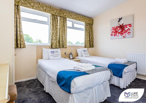 two beds in a room with two windows at Dene Hotel in Newcastle upon Tyne