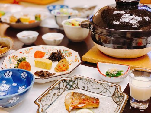 a table with plates of food and a tea pot at Kappo Ryokan Yumesaki in Beppu