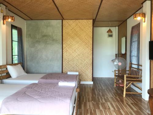 a bedroom with two beds and a table and a tv at บ้านกลางเกาะ รีสอร์ท in Uthai Thani