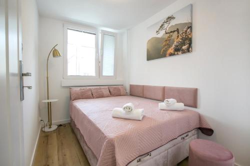 um quarto com uma cama rosa com duas toalhas em Duszniki Zdrój 1 em Duszniki Zdrój
