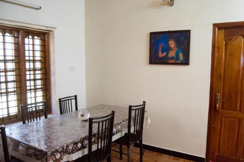 a dining room table with chairs and a painting on the wall at Texas Guest house in Trivandrum