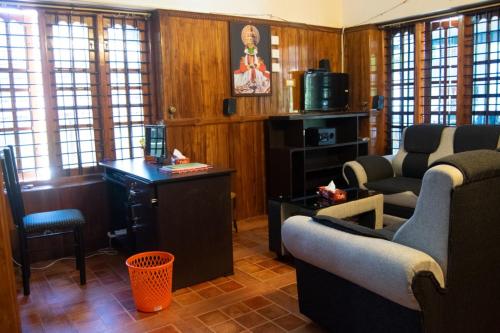 - un salon avec deux chaises, un bureau et des fenêtres dans l'établissement Texas Guest house, à Trivandrum