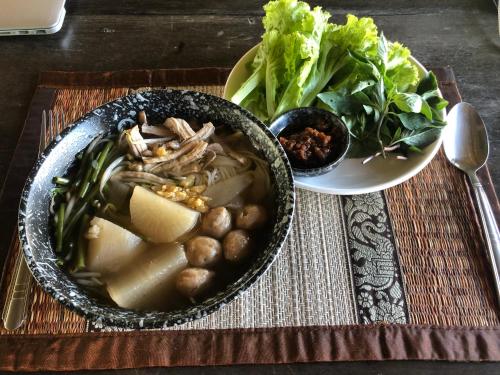 a table with a bowl of soup and a plate of salad at On The Mekong Resort in Luang Prabang