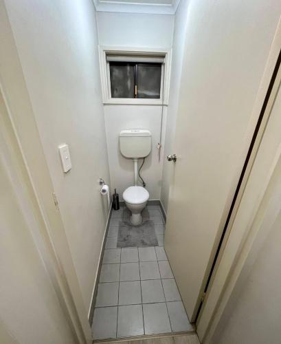 a small bathroom with a toilet and a window at 1 bed room - Cozy unit in Cheltenham