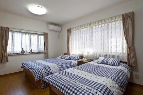 two beds in a room with two windows at japan house shinkoiwa guest house in Tokyo