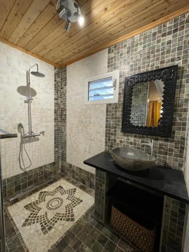 uma casa de banho com um lavatório e um espelho em L’anthurium em Saint-Paul