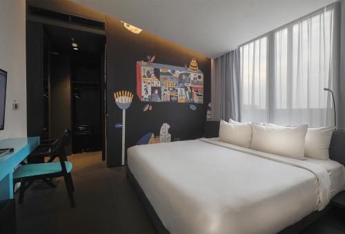 a bedroom with a large white bed and a desk at ARTOTEL Gajahmada Semarang in Semarang