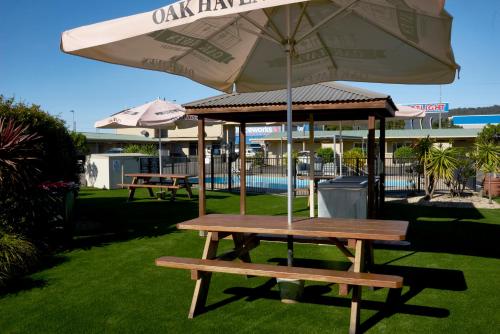 a picnic table with an umbrella next to a pool at Ashwood Motel in Gosford