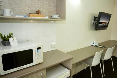 a kitchen with a microwave on a counter with chairs at Ashwood Motel in Gosford