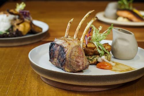 a plate of food with a piece of meat on a table at ARTOTEL Gajahmada Semarang in Semarang