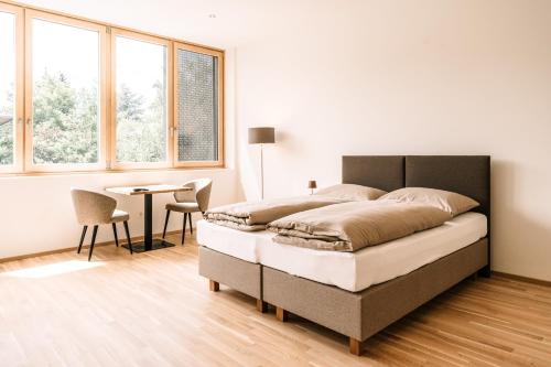 Schlafzimmer mit einem Bett, einem Tisch und Fenstern in der Unterkunft LOOMZ living Self-check-in in Innsbruck
