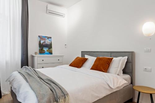 una camera da letto con un letto con lenzuola bianche e cuscini arancioni di VD Boutique Apartments No 1 Bucharest a Bucarest