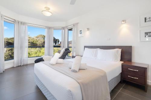 een slaapkamer met een groot bed met witte lakens en ramen bij Rye Treetop Retreat in Rye