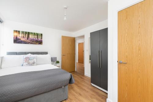 a bedroom with a bed and a wooden door at Skyvillion - 4 Bed Luxury Apartment with Balcony & Parking in Enfield