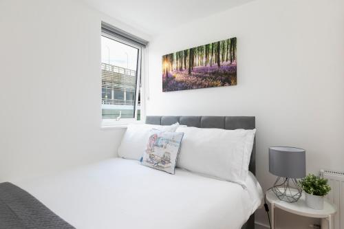 a bedroom with a white bed and a painting on the wall at Skyvillion - 4 Bed Luxury Apartment with Balcony & Parking in Enfield