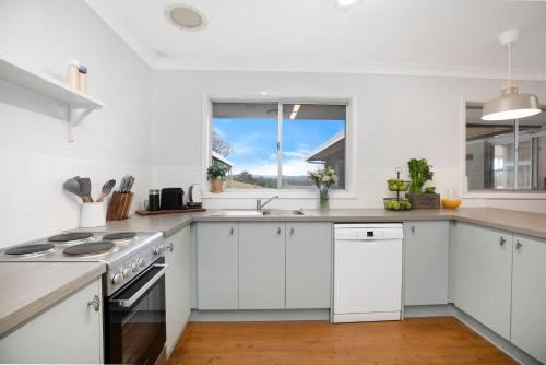 a kitchen with white cabinets and a stove top oven at Hillside Farm in Mittagong