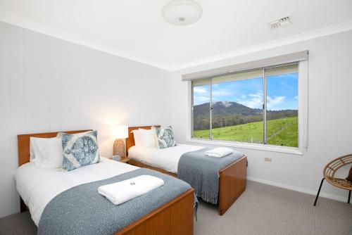 2 camas en una habitación con ventana en Hillside Farm, en Mittagong