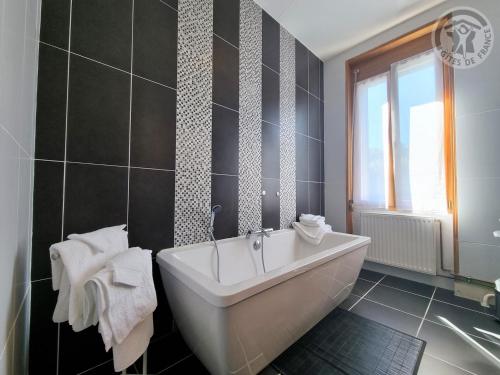 La salle de bains est pourvue d'une baignoire blanche et d'une fenêtre. dans l'établissement Gîte de charme à Cambrai : 3 chambres, jardin, garage, proche centre et gare - FR-1-510-178, à Cambrai