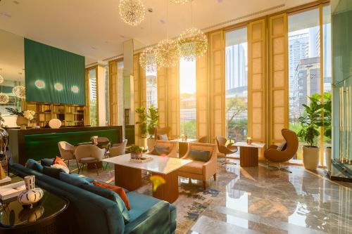 a living room with couches and tables and windows at SQ Boutique Hotel in Bangkok