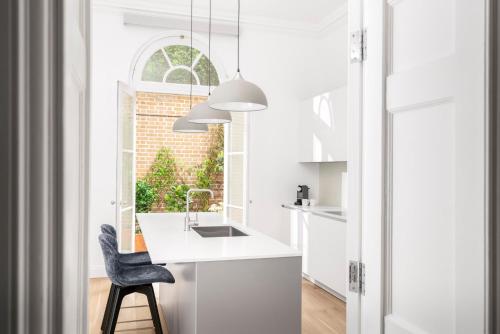 a kitchen with a white counter and a black chair at COMO Metropolitan London in London