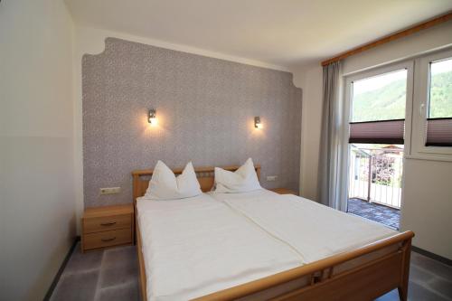 a bedroom with a bed with white sheets and a window at Apartments Luidold in Schladming