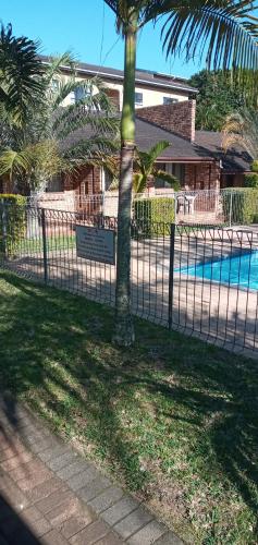 a fence with a palm tree in front of a pool at Flamboyant Apartments in St Lucia