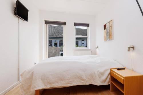 a white bedroom with a bed and a window at Hotel Rudkøbing Skudehavn Apartments in Rudkøbing